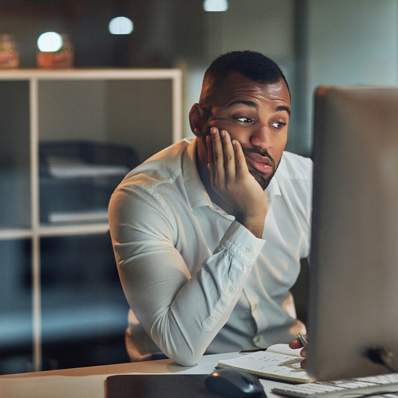 Man sitting at computer monitor looking bored